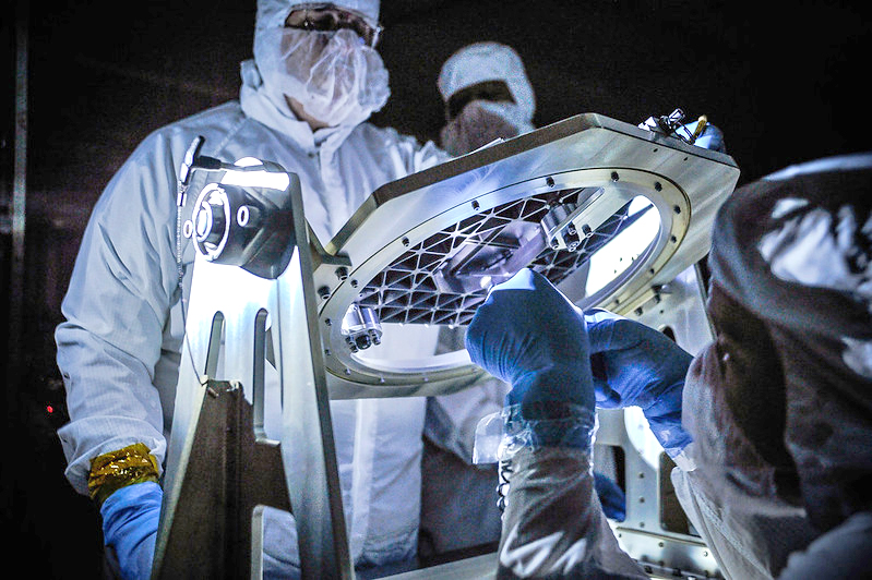 scientists in clean suits, inspecting telescope apparatus